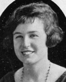 A smiling young white woman with dark hair cut in a short bob with bangs