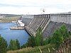 A large concrete structure damming a river with an adjacent building used for hydroelectric generation