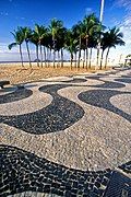 Wave-patterned Portuguese pavement in Avenida Atlântica, with the Cagarras Islands in the background.