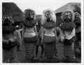 Five masked people in costume with sticks, 1936