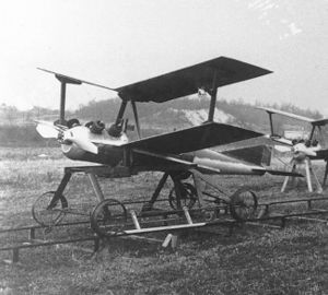 a small unmanned biplane aircraft resting on a pair of rails