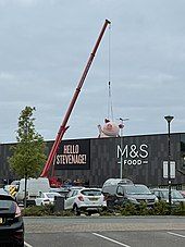 A crane hoisting a giant statue of the Percy Pig character up to the roof of the newly opened store in Stevenage.