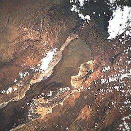 Satellite image of portion of lake with clouds in forground.