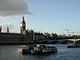 A large clock tower and other buildings line a great river.