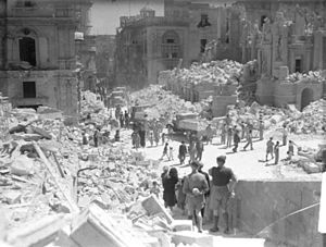 Service personnel and civilians clear up debris on a heavily bomb-damaged street in Valletta, Malta, on 1 May 1942.