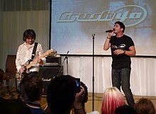 Jun Senoue with a guitar and Johnny Gioeli with a microphone