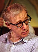 Photo of a bespectacled Jewish male looking toward his left shoulder. He is wearing an unbuttoned gray collared shirt.