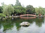 Pond with a stone inside and a red bridge crossing it.