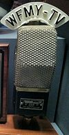 An old microphone with a custom W F M Y - TV label on the top