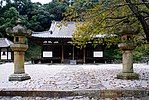 Wooden building with slightly raised floor, white walls and a hip-and-gable roof.