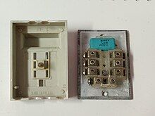 A GTN-6 plug disassembled into two parts, the plastic cover on the left and the internal electronics on the right. Above the terminal block is visible a blue capacitor.