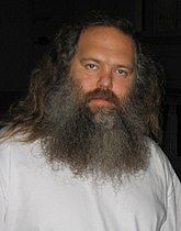 A man in a white shirt with long gray hair and a long beard