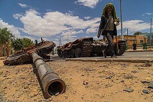 A man passing by a destroyed T-72 tank in Idaga Hamus during Tigray war.