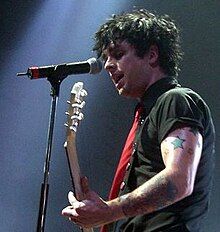 Billie Joe Armstrong playing an electric guitar while singing into a microphone