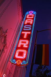 Seen from below, a neon sign that reads "CASTRO" in vertical letters is lit against a night sky.