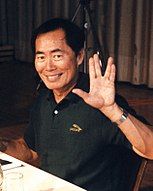 An Asian man wearing a black shirt gives a Vulcan salute.