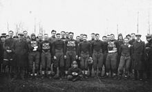 Black and white photo of football players standing in uniform.