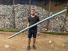 A man holding a board made from plastic in front of bags of PET bottles.