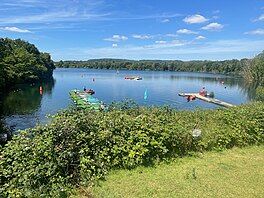 View over lake with two pontoons extending into the water and trees lining the opposite shore in the distance