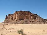 A large, square-shaped mound made up of dirt and rock in the middle of a deserted area.