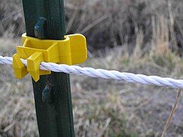 Detail of electric cord fence with metal interwoven with nylon cord, attached to a steel fence post with a plastic insulator