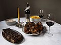 Typical Christmas table in Serbia. Grilled pork, Olivier salad (also called Russian salad), tzatziki dip, red wine and Bajadera sweets