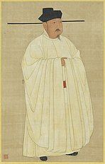 Painted image of a man standing erect, wearing white silk robes, black hat, black shoes, and sporting a black mustache and goatee