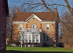 A two-story gabled stone house with a protruding centered sun room