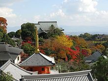 Several Buddhist buildings among the trees in autumn colours.