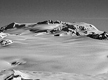 Black and white photo of a flat-topped, snow-covered mountain summit.