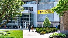 students walking from a concrete building past green trees