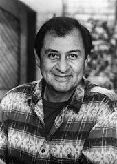 Black-and-white headshot of a man wearing a printed shirt with stripes.