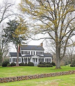 A white, two-story house with one-story wings