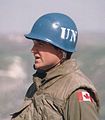 a person in a military uniform wearing a United Nations blue helmet