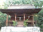 Small wooden building with a curved roof and stairs leading to a platform surrounding the building.