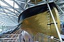 ☎∈ The restored stern (with stern draft and rudder) of the Cutty Sark elevated 3 metres above its dry-dock under its glass-roofed visitors' centre in June 2012.