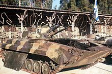 Two damaged armored personnel carriers. An Israeli flag is next to them.