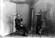 In this 1893 multiple-exposure trick photo, the photographer appears to be photographing himself. It satirizes studio equipment and procedures that were nearly obsolete by then. Note the clamp to hold the sitter's head still.