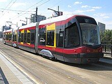 Tram in red and grey livery with irregular yellow shapes around some windows