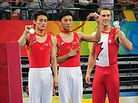 Three gymnasts holding their Olympic medals in their hands