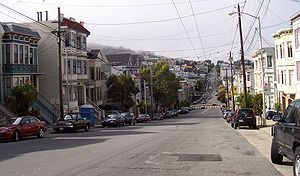 Eureka Valley, looking north on Castro Street from 20th. The giant rainbow flag at Castro and Market is just visible. In the summer months, fog tends to roll in over Twin Peaks and other hills to the west in the evenings and retreat again the next morning.