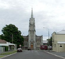 A view of a street with a large church spire at the end