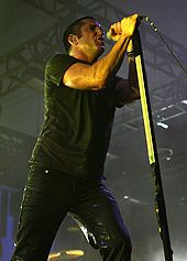 A man dressed in all black singing into a microphone.