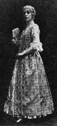 A white woman wearing a costume including a wig and a long print gown in 18th-century style