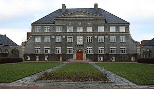 Large, grey building behind a grassy area