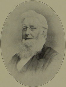 An elderly man with a white beard and glasses, wearing a suit, depicted in an oval-shaped vintage photograph.