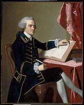 Full-length portrait of a young man seated at a table - he wears a finely tailored dark suit, knee breeches with white stockings, and a wig in the style of a European gentleman. He holds a quill pen in his right hand, and is turning the pages of a large book with the other hand.