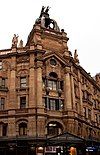 Red sandstone frontage in the ornate and French Renaissance style and with a theatrically Baroque skyline. The wording "London Hippodrome" face to the front on the upper level, also in red sandstone