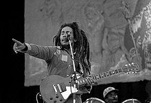 Black and white image of Bob Marley on stage with a guitar