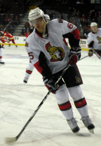 Man skating on rink wearing hockey equipment